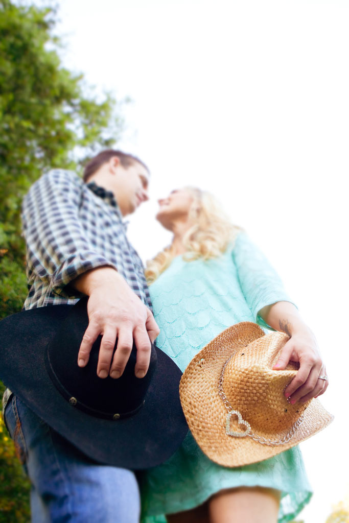Engaged coupple holding cowboy hats